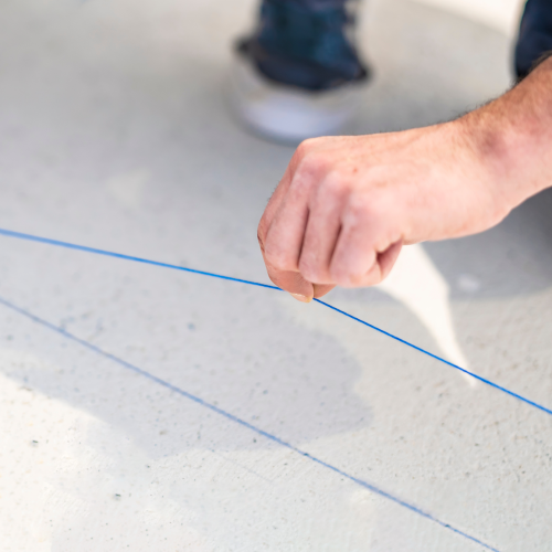 Hand holding a blue line on a white surface